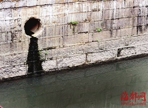 內河一處排污口，正在流出墨黑色污水。